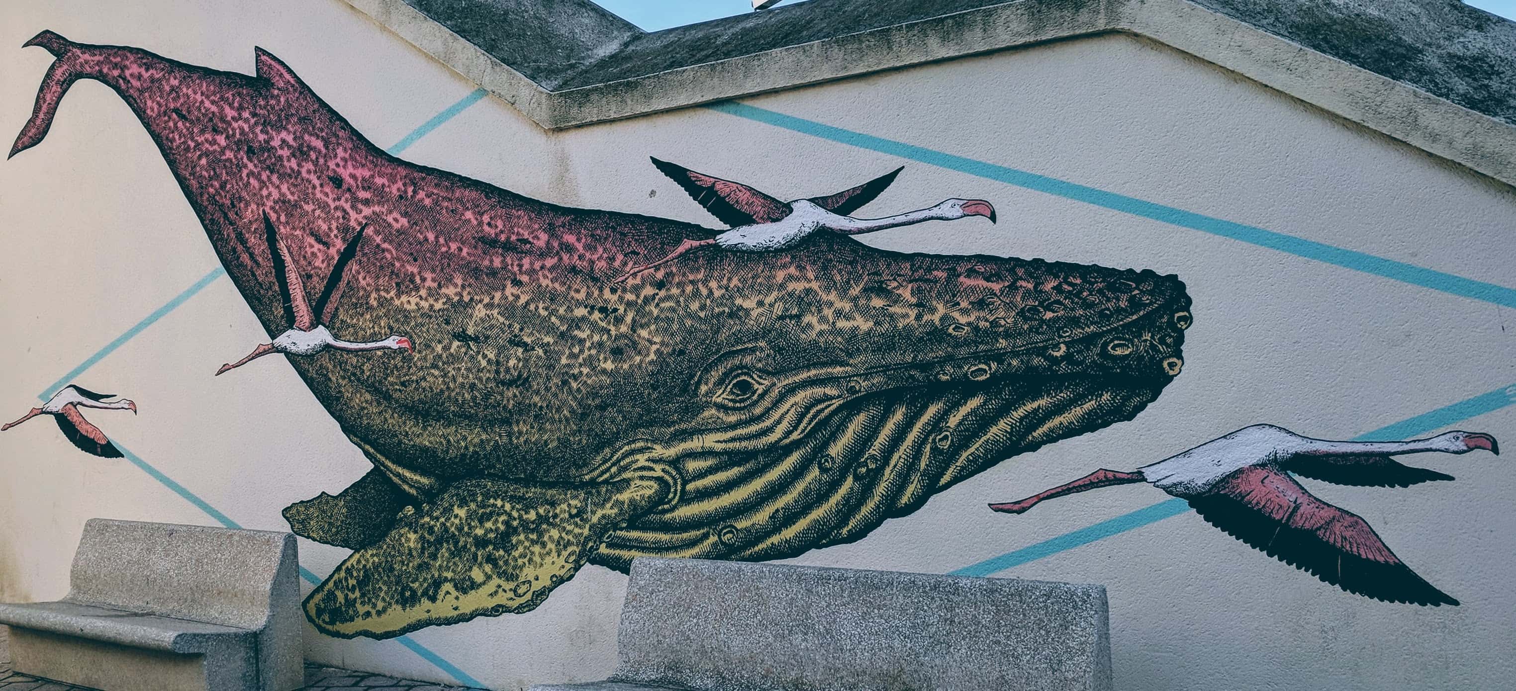 Graffiti of a whale surrounded by flying flamingos